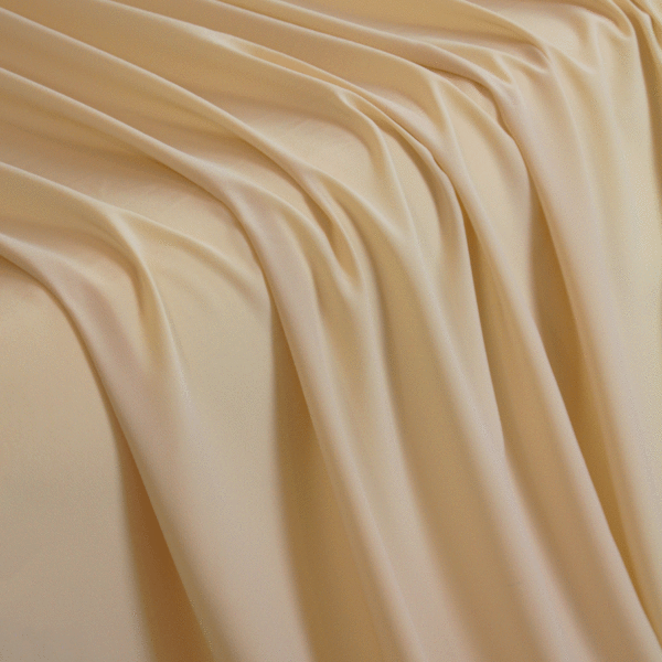 A solid ivory crepe wool dobby fabric flowing over a table in a waterfall pattern.