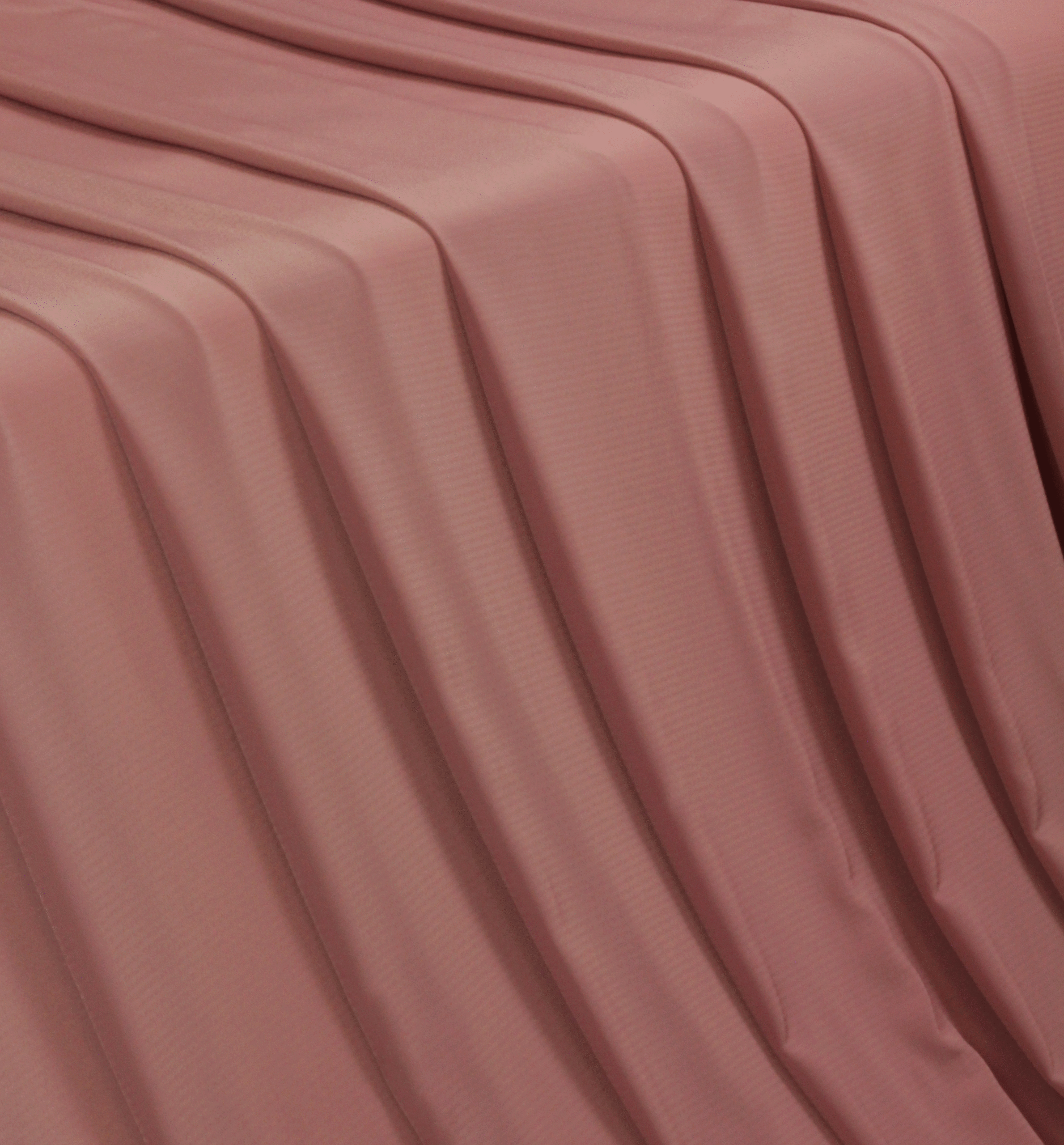 A solid mauve crepe wool dobbyfabric flowing over a table in a waterfall pattern.